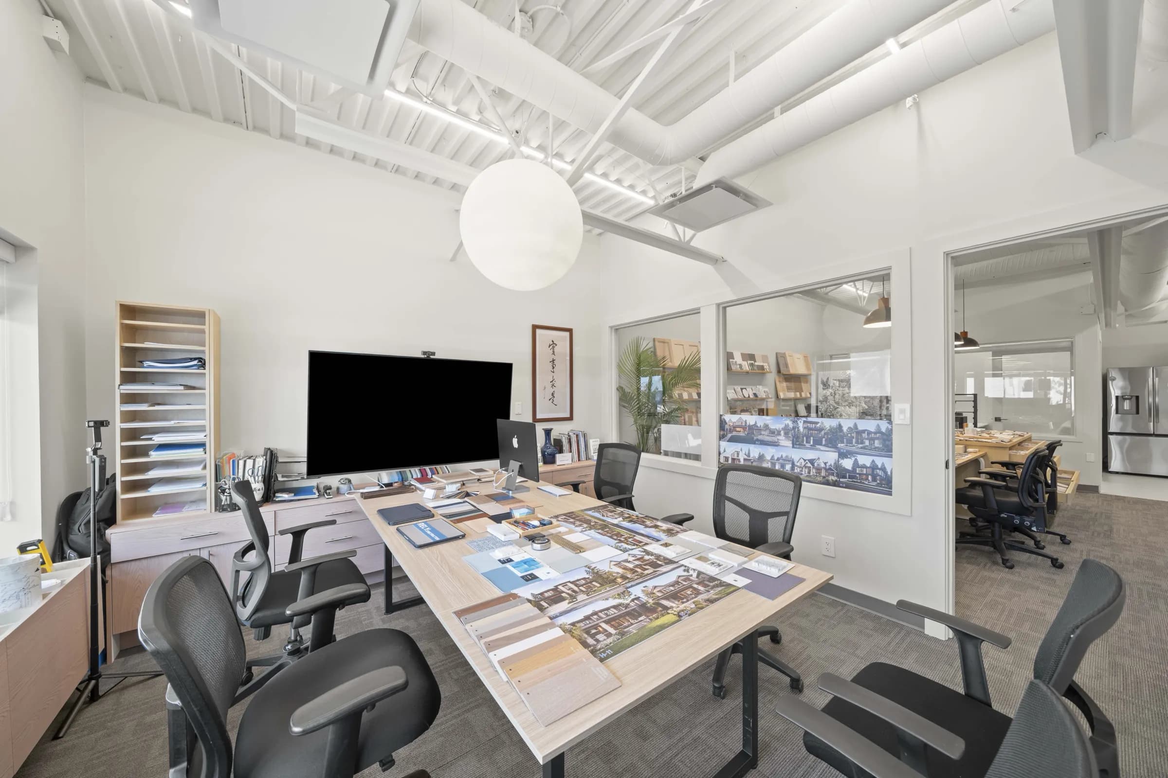 Drawings and finish boards laid out across the meeting table in Rely Construction's Richmond studio